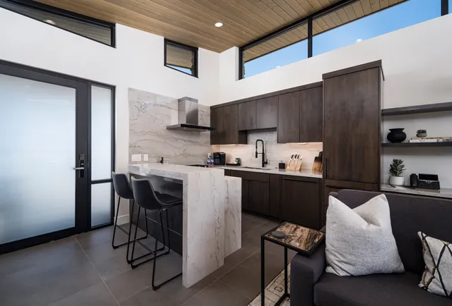 Kitchen with a stone island, bar stools and dark wood cabinets