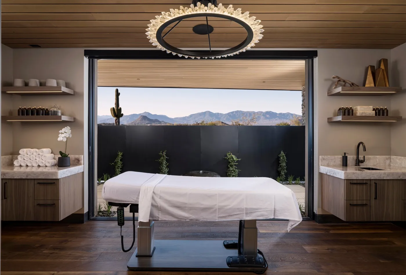 Spa treatment room with a massage table and a wide opening onto the desert